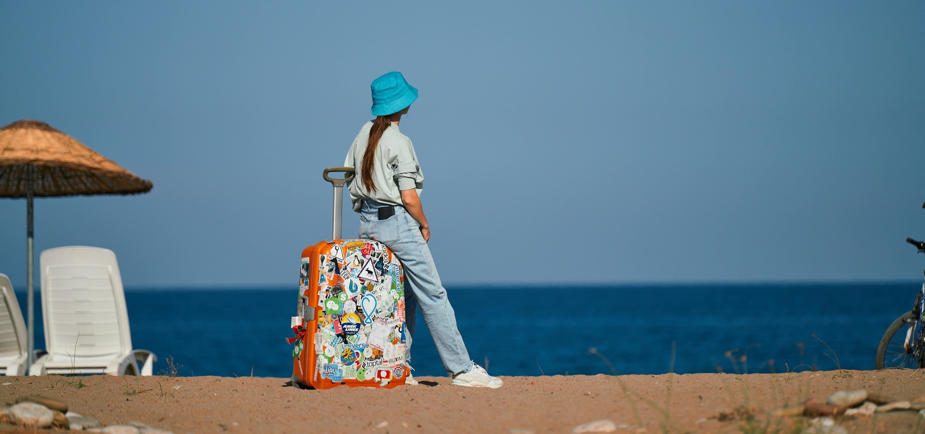 Solo traveler with a suitcase on a beach in Cyprus overlooking the sea