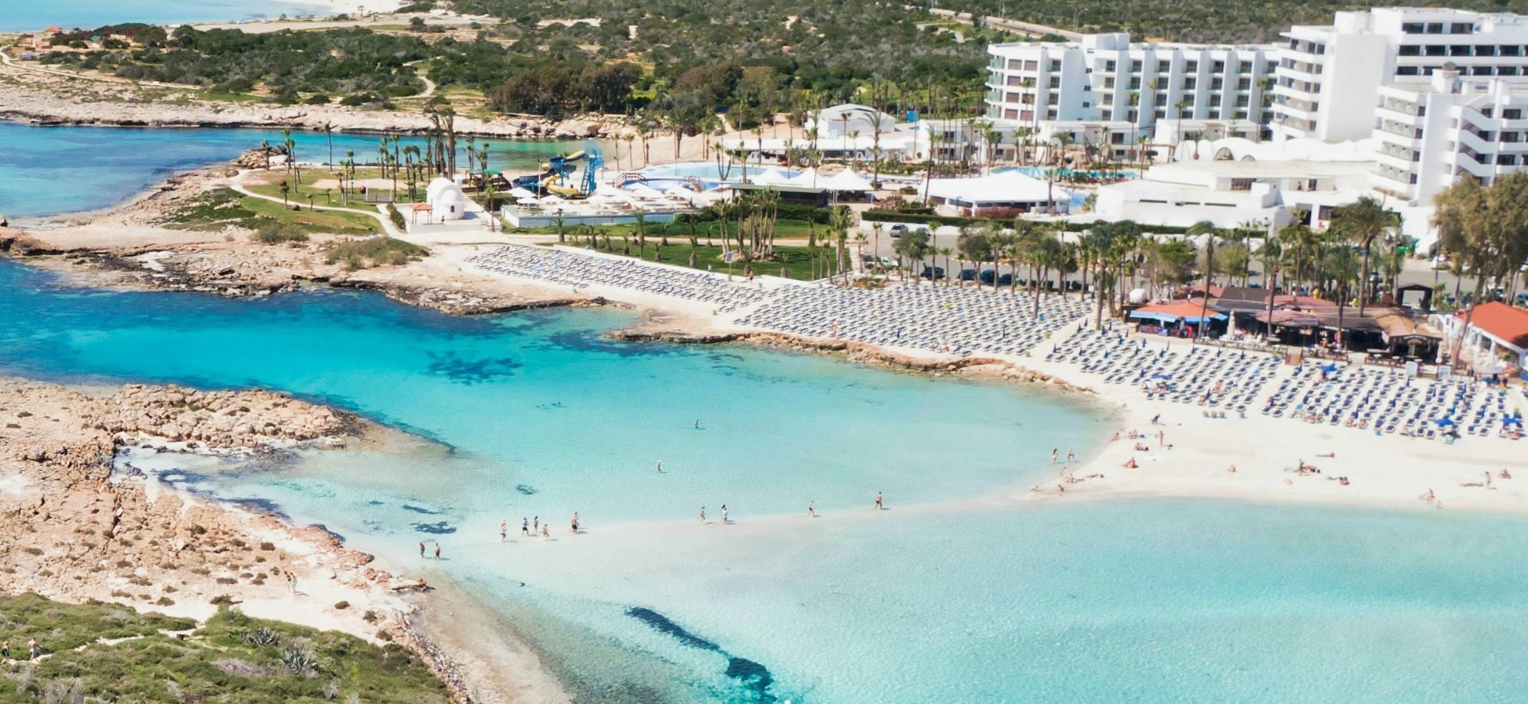  A beach resort with a white hotel and turquoise water in Ayia Napa