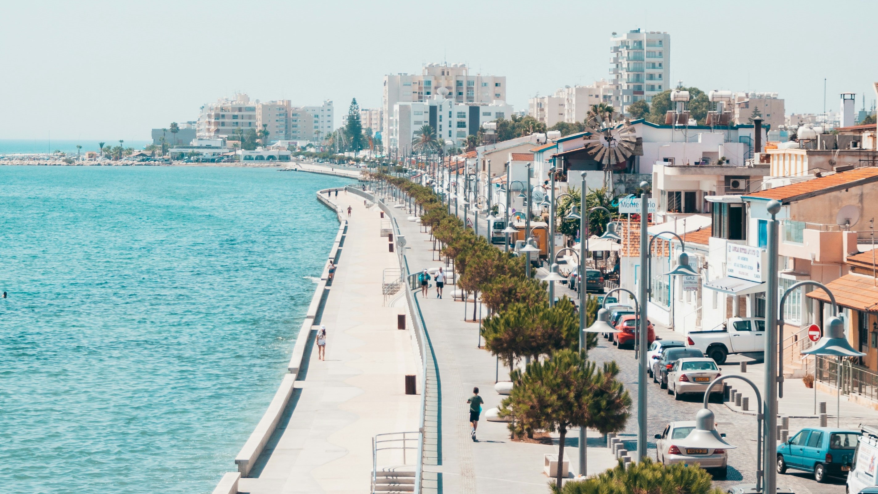 A coastal walkway lined with palm trees and colorful buildings in Larnaca