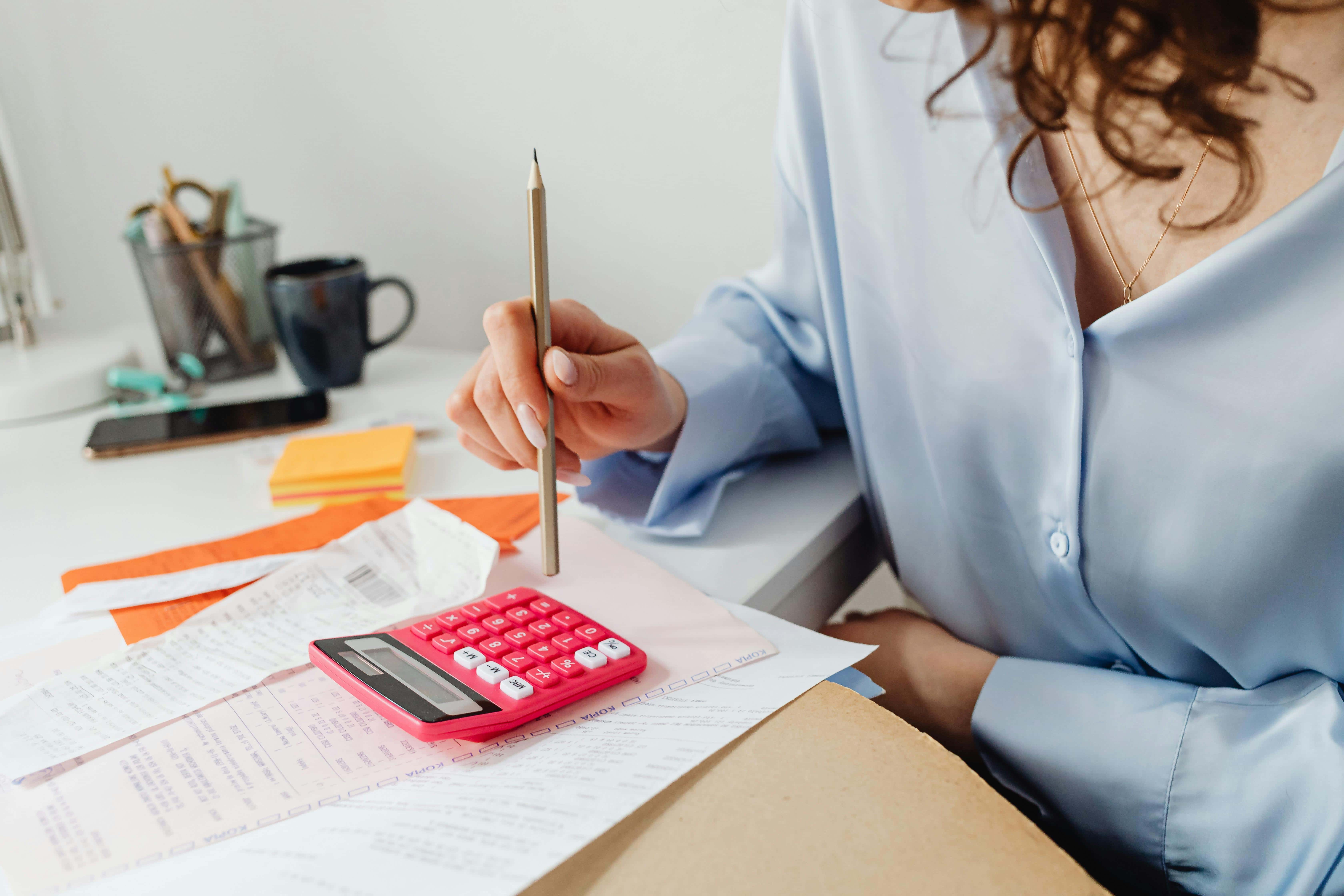 A woman in a blue shirt calculates taxes on a calculator