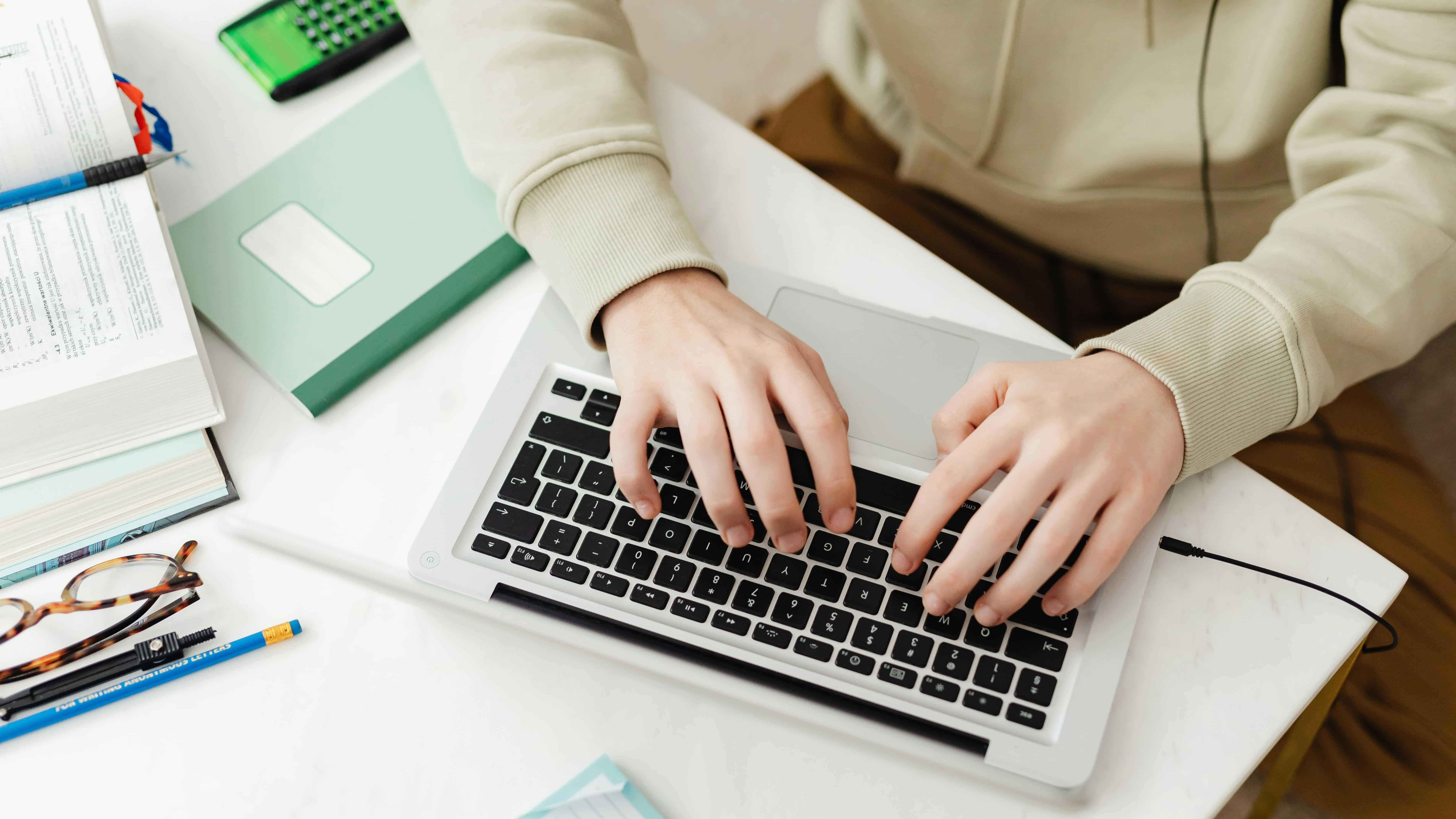 A person typing on a laptop while searching the Internet