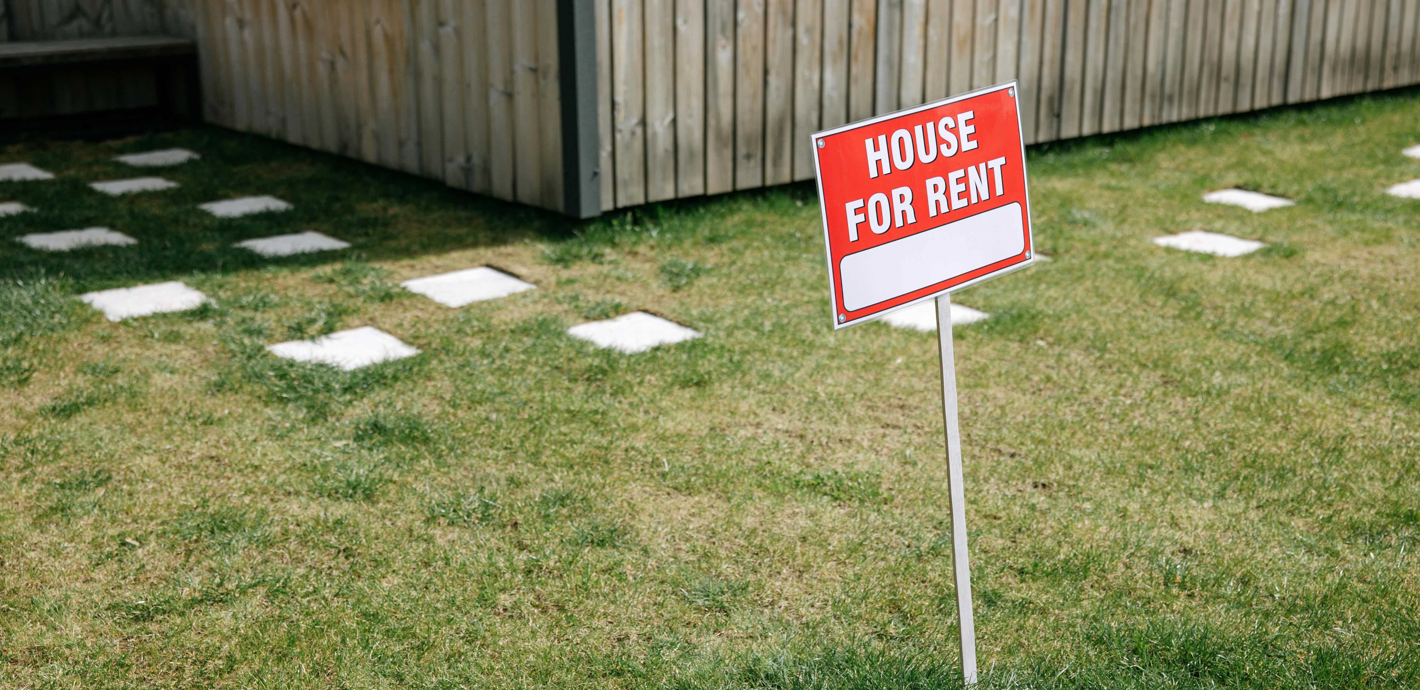 modern house with a sign “house for rent”