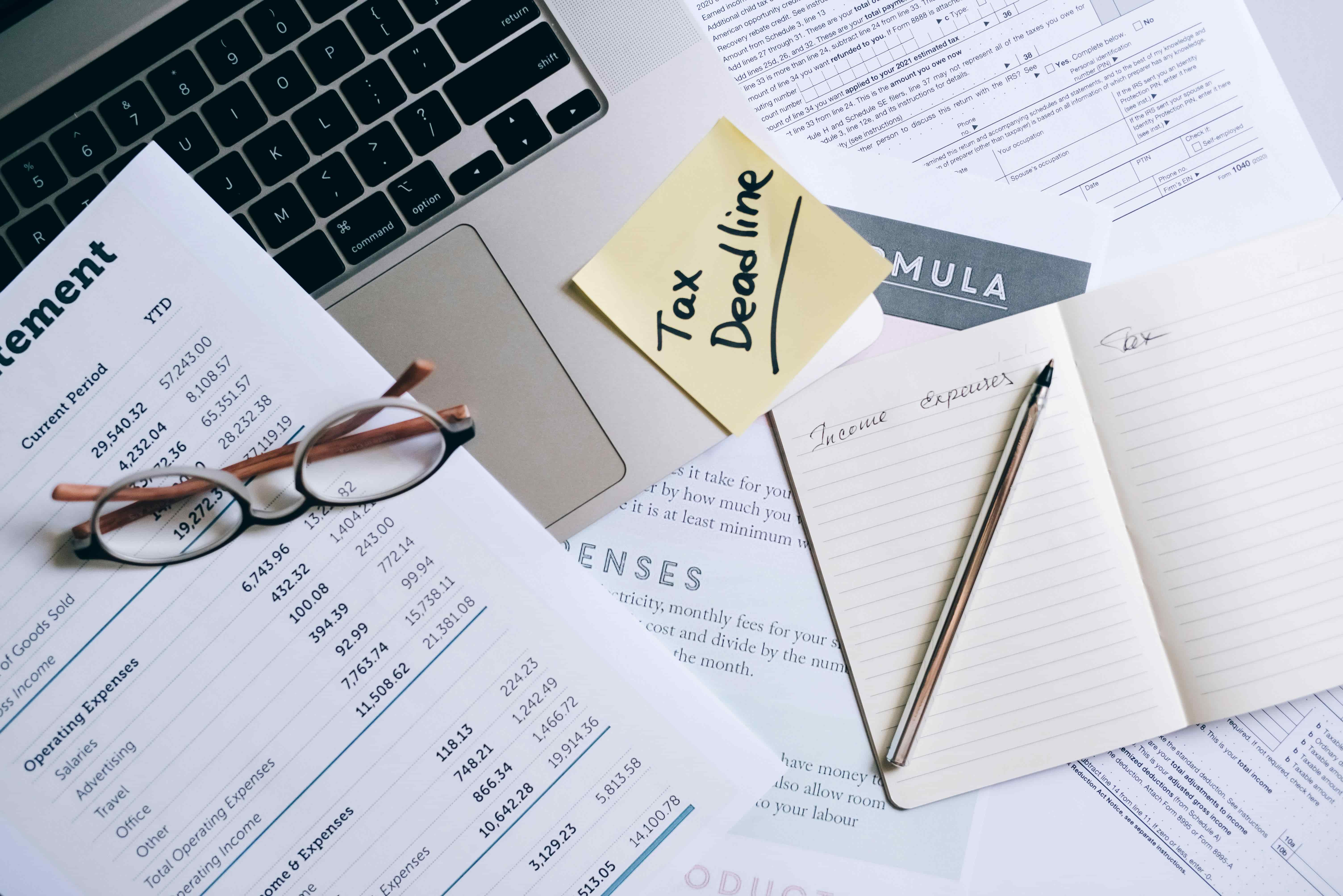 A Notebook and Pen Near the Laptop and Documents on the Table